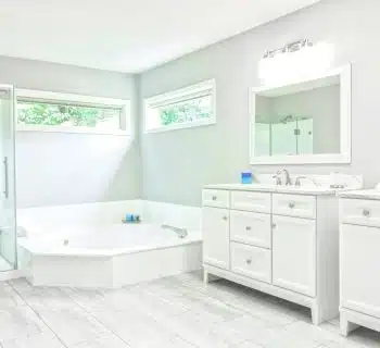 white ceramic bathtub near white wooden vanity sink